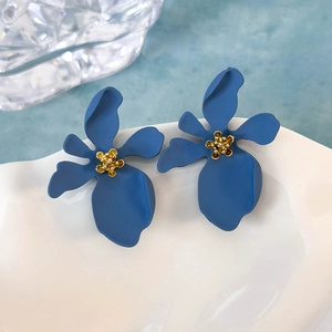 Dettaglio degli orecchini a fiore blu opaco con anima dorata su un piatto bianco