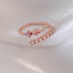 Close-up of adjustable rose gold ring with pearls and multi-colored cubic zirconia stones