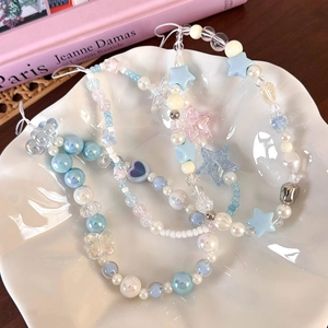 Three beaded phone charms with sea salt blue stars and pearls in a white ceramic dish