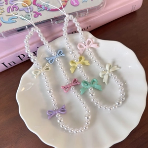 Macro detail of colorful bow beads and white pearls on a stylish phone charm strap