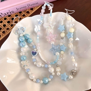 Blue and pink beaded phone charms with stars and pearls on a white ceramic plate