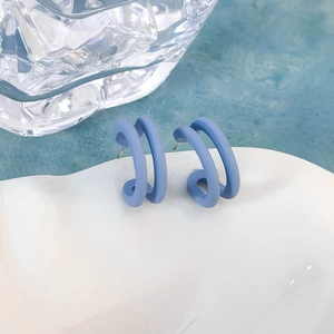 Dettaglio di orecchini a doppio cerchio blu opaco su vassoio decorativo in ceramica