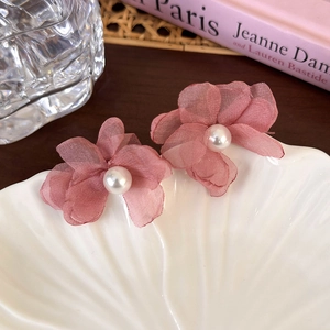 Détail de boucles d'oreilles fleurs en mousseline rose avec perles sur coquillage