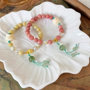 Close-up of Neo-Chinese beaded bracelets with jade tassels in a shell-shaped dish