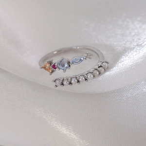 Detail of adjustable open ring featuring colorful gemstones and pearls on white satin