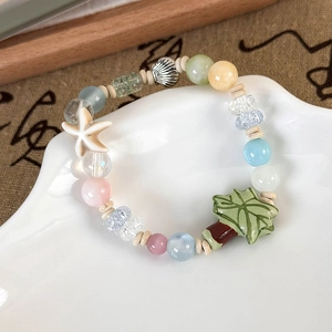 Detail of colorful beaded bracelet featuring a starfish, shell, and palm leaf charms