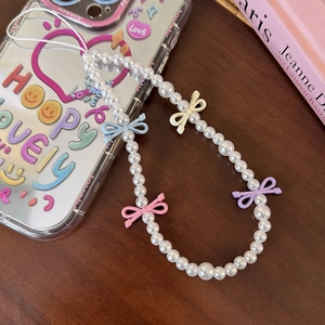 Detailed macro view of white pearl phone lanyard featuring colorful mini metal bow charms