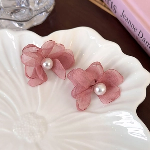 Gros plan de boucles d'oreilles fleurs en mousseline rose avec perle centrale
