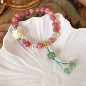 Detail of beaded tassel bracelet with pink crystals and white carved lion dance motif