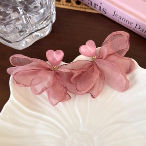 Vue détaillée des boucles d'oreilles cœur rose avec pétales en organza sur assiette blanche