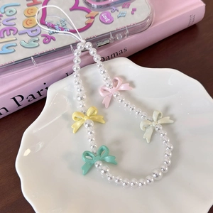 Close-up of colorful bow charms and imitation pearls on a sweet beaded phone strap