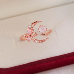 Detail of rose gold moon ring featuring pink gemstone flowers on velvet
