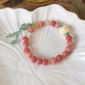 Close-up of pink marble beads and a white carved lion pendant on a beaded tassel bracelet