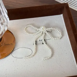 Detail of elegant pearl bow hair clip with creamy faux pearls on a display tray