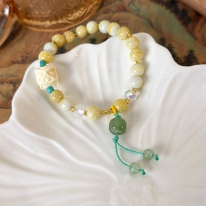 Detailed macro view of beaded tassel bracelet with white lion head carving and jade beads