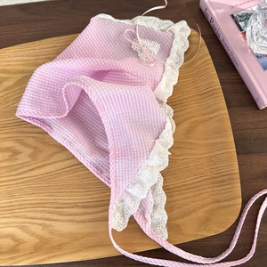 Detail of pink plaid headscarf with white floral lace trim on a wooden tray