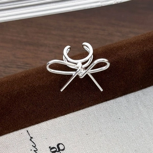 Détail macro de la boucle d'oreille nœud en argent sur présentoir en velours