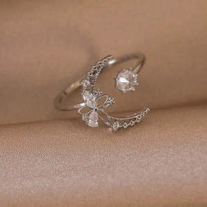 Detailed view of silver crescent moon and zircon flower ring on champagne silk