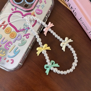 Detail of beaded phone strap with pearls and colorful bows on a cute transparent phone case