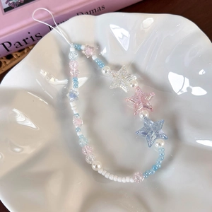 Close-up of sea salt blue star beads and pearls mobile phone charm on a white ceramic plate