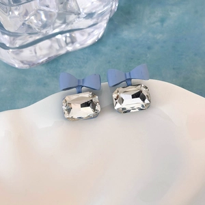 Dettaglio macro di orecchini a fiocco blu con strass rettangolare trasparente