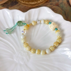 Detail of Chinese style beaded bracelet with lion pendant on ceramic petal tray