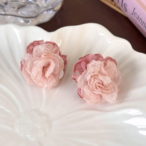 Détail macro de boucles d'oreilles fleurs en mousseline rose avec des pétales superposés
