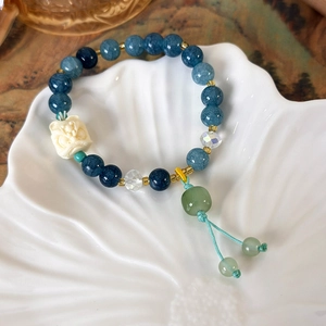Detail of beaded tassel bracelet with white lion pendant on shell ceramic plate