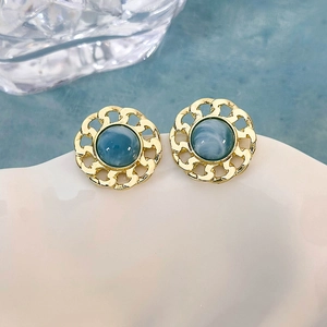 Dettaglio di orecchini d'oro vintage con pietra blu marmorizzata e catena decorativa
