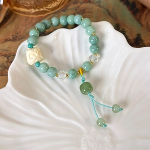 Macro shot of Neo-Chinese beaded bracelet with lion pendant and tassels on a white plate