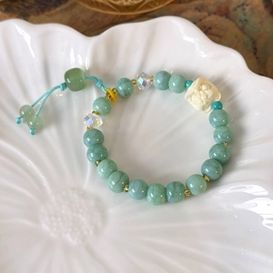 Detail of teal bead bracelet with white carved charm and blue tassel on flower tray