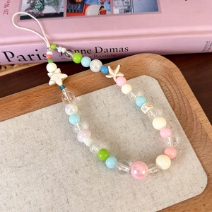 Détail des perles pastel avec breloques étoile de mer sur un support en tissu doux