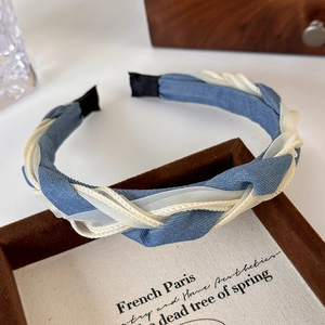 Close-up of braided denim and white mesh headband displayed on a brown velvet tray