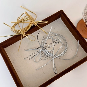 Metallic silver and gold bow hair accessory displayed on a vintage velvet jewelry tray