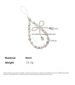Detail of beaded pearl phone wrist strap with resin bow and rhinestone spacers