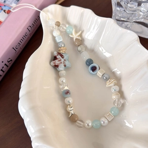 Détail d'une dragonne de téléphone en perles avec étoiles de mer et coquillages