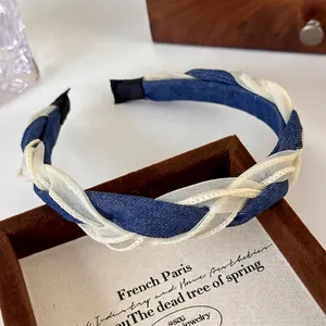 Detailed shot of braided denim and organza headband in a luxury display box