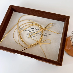 Detail of golden metallic bow hair ties on a vintage tray with French Paris text