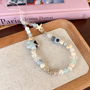 Détail d'une dragonne de téléphone en perles avec étoile de mer et perles étoiles