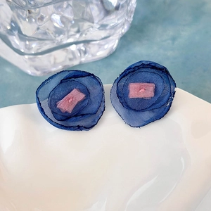 Dettaglio orecchini a fiore in organza blu con delicato tessuto e centro rosa cipria