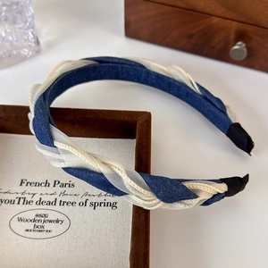 Detail view of braided denim and mesh headband resting on a brown jewelry box