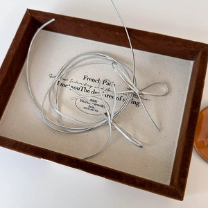 Detail view of metallic silver bow hair ties with Y2K balletcore style on a display tray