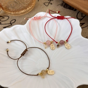 Detail of woven adjustable bracelets with colored gemstone beads and lucky gold charms