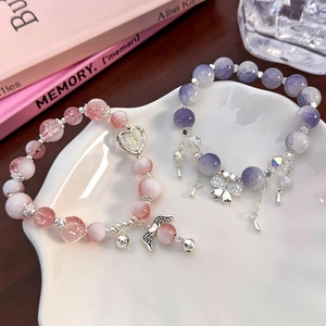 Pink and blue crystal bead bracelets with butterfly and wing charms on a white ceramic plate