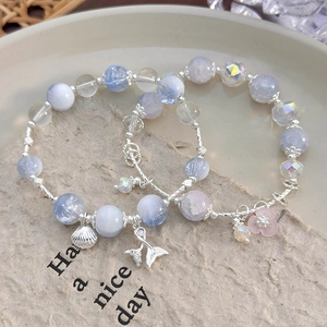 Detail of beaded bracelets with blue crystal beads, shell and fish tail pendants