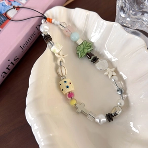 Détails de la dragonne de téléphone bohème avec perles et étoile de mer sur plateau