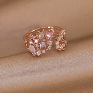 Detailed close-up of rose gold flower ring with crystals and pearls on silk fabric