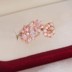 Detail of rose gold open ring with pink crystals and pearls on beige velvet
