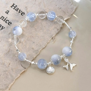 Close-up of beaded bracelet with light blue crackle beads and silver fish tail shell charms