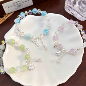 Colorful crackle crystal beaded bracelets with heart, fishtail, and cat charms in a dish
